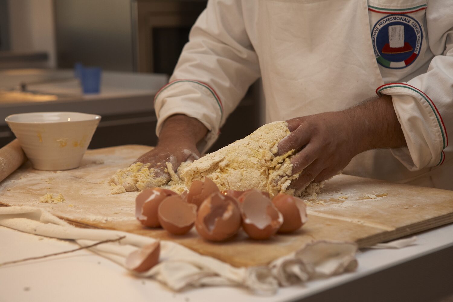 A chef making fresh pasta by hand in a villa kitchen