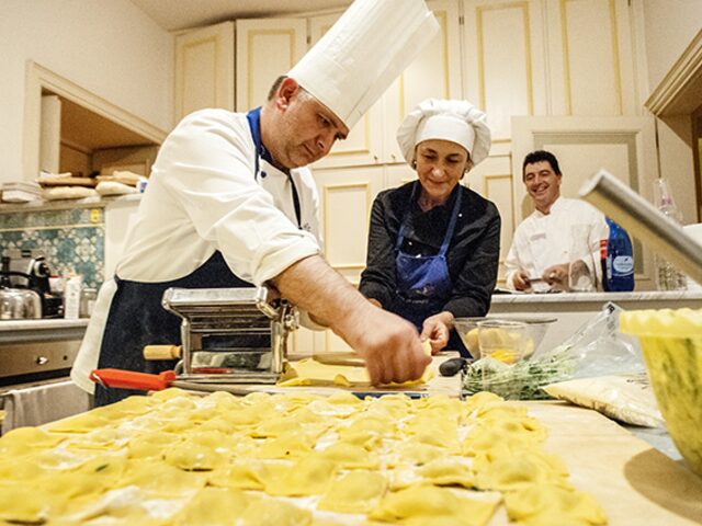 A cook teaching how to roll out pasta during a cooking class